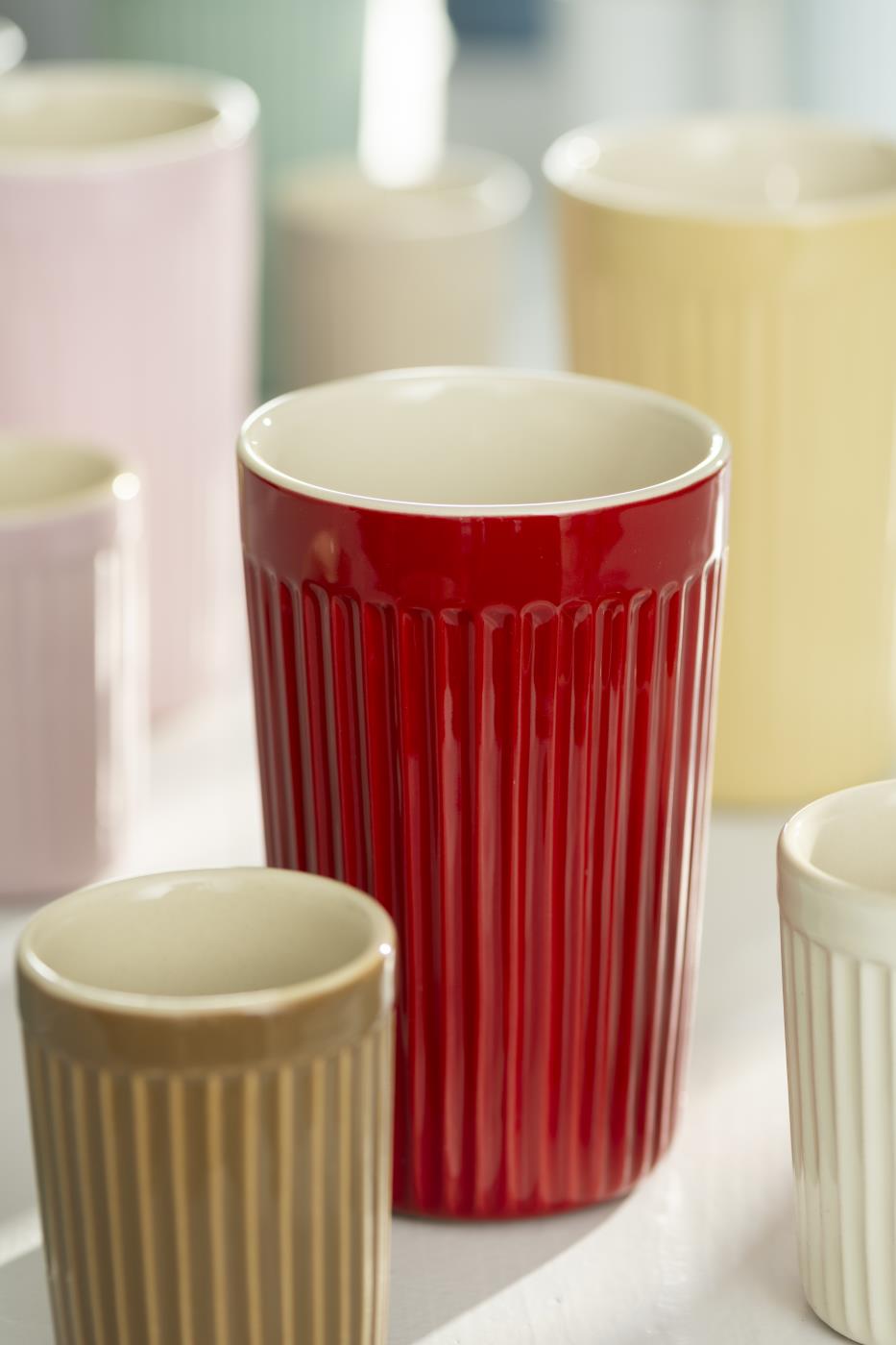Mehrere Tassen in verschiedenen Farben und Größen stehen auf einem Tisch. Die Tassen haben eine gerippte Oberfläche.
