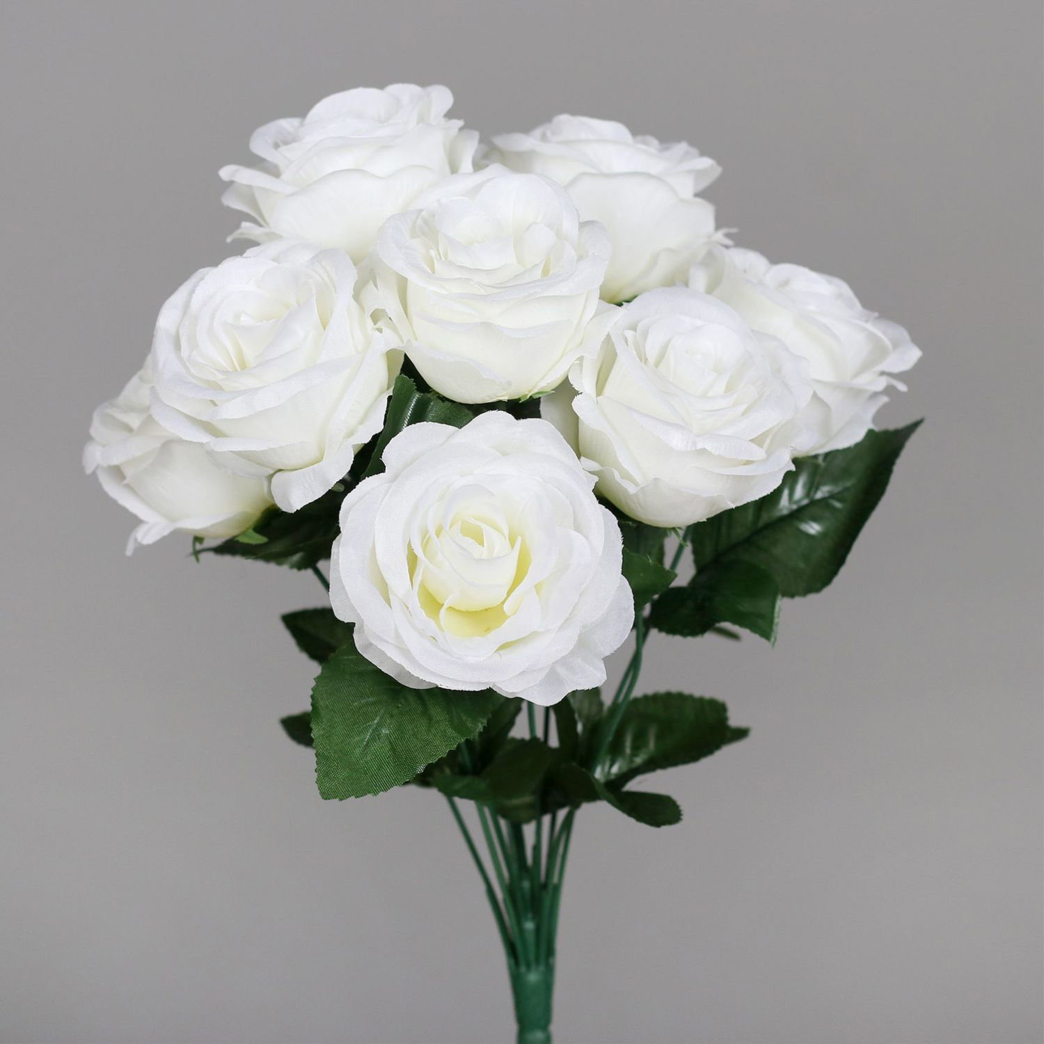 Strauß weißer Rosen mit grünen Blättern vor grauem Hintergrund