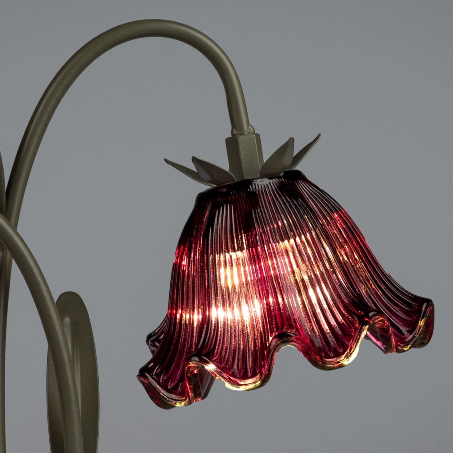 Eine Tischlampe mit einem rot-transparenten, gewellten Glasschirm und einem metallenen Gestell.