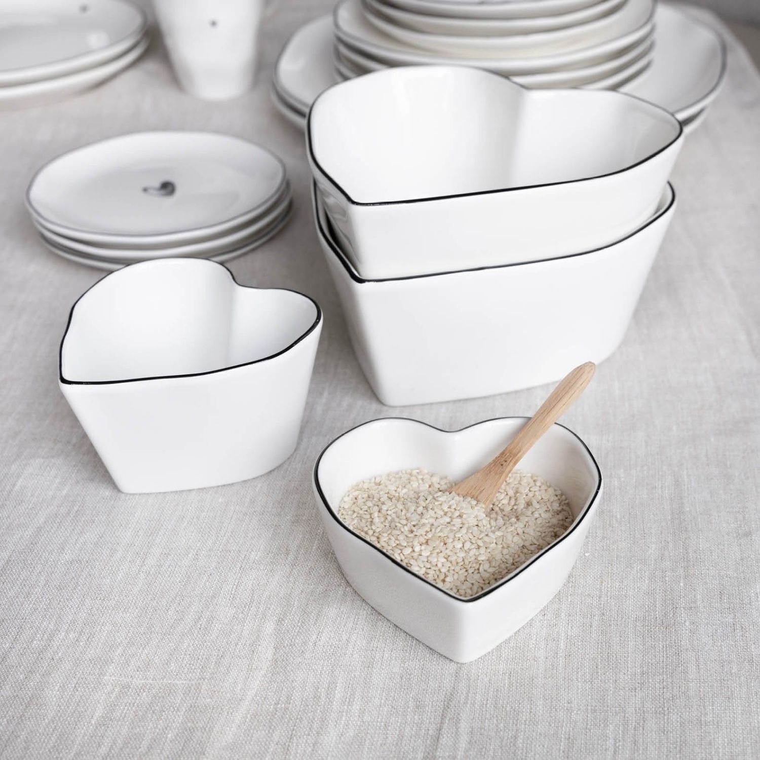 Herzförmige Schalen aus weißem Porzellan mit Reis darin und Holzlöffel