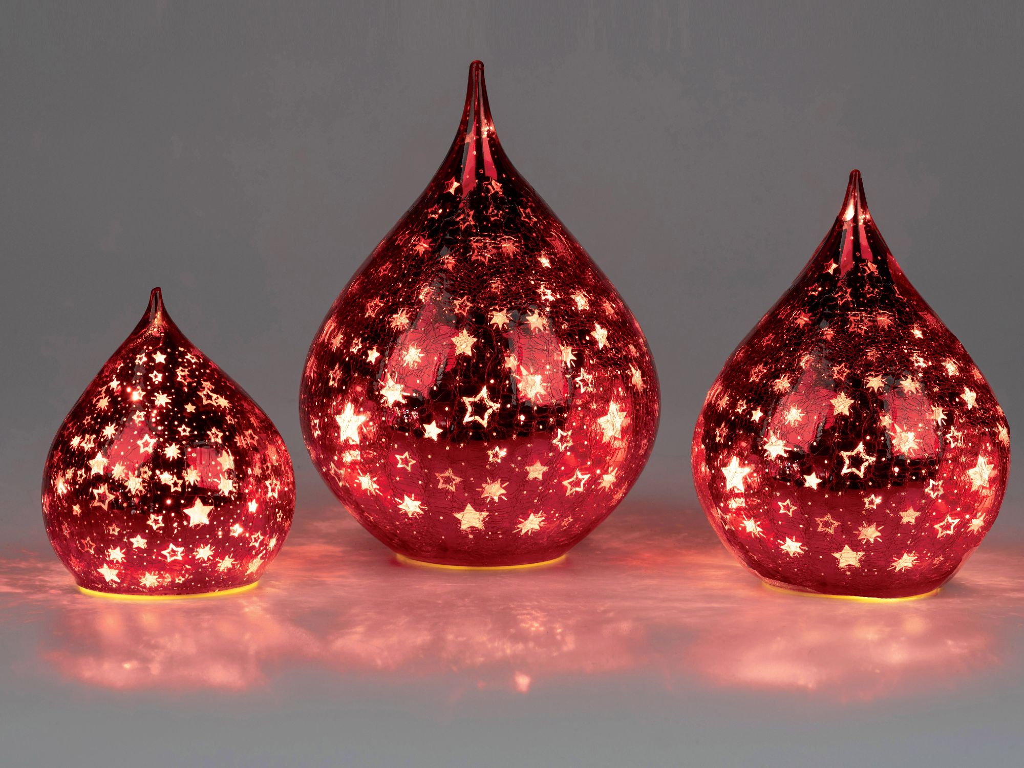 Drei rote, gläserne Leuchten in Tropfenform mit leuchtenden Sternenmustern, unterschiedlich groß, au