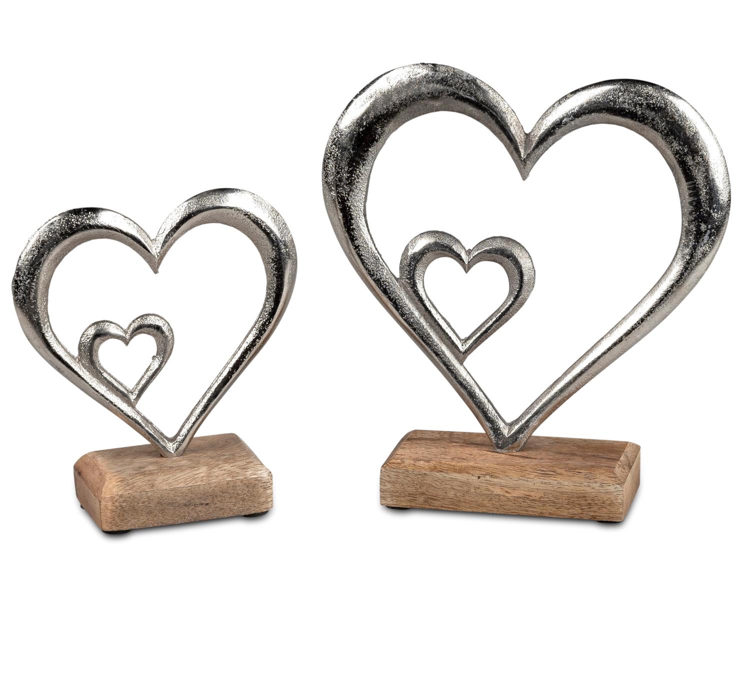 Zwei dekorative Herzskulpturen aus Metall, eine größere und eine kleinere, auf Holzsockeln platziert.