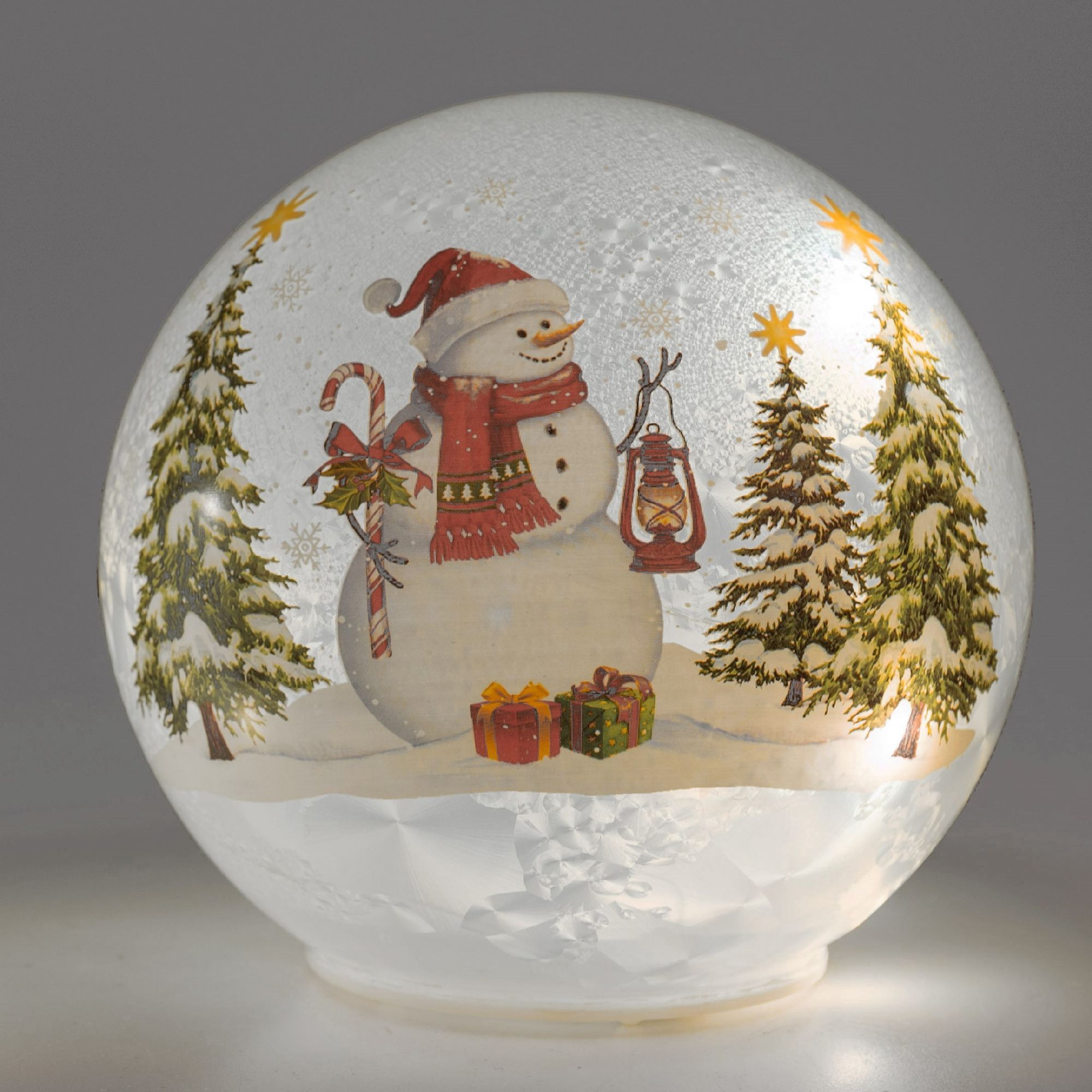 Schneekugel mit einem Schneemann, Tannenbäumen, Geschenken und einer Laterne, umgeben von Schneefall