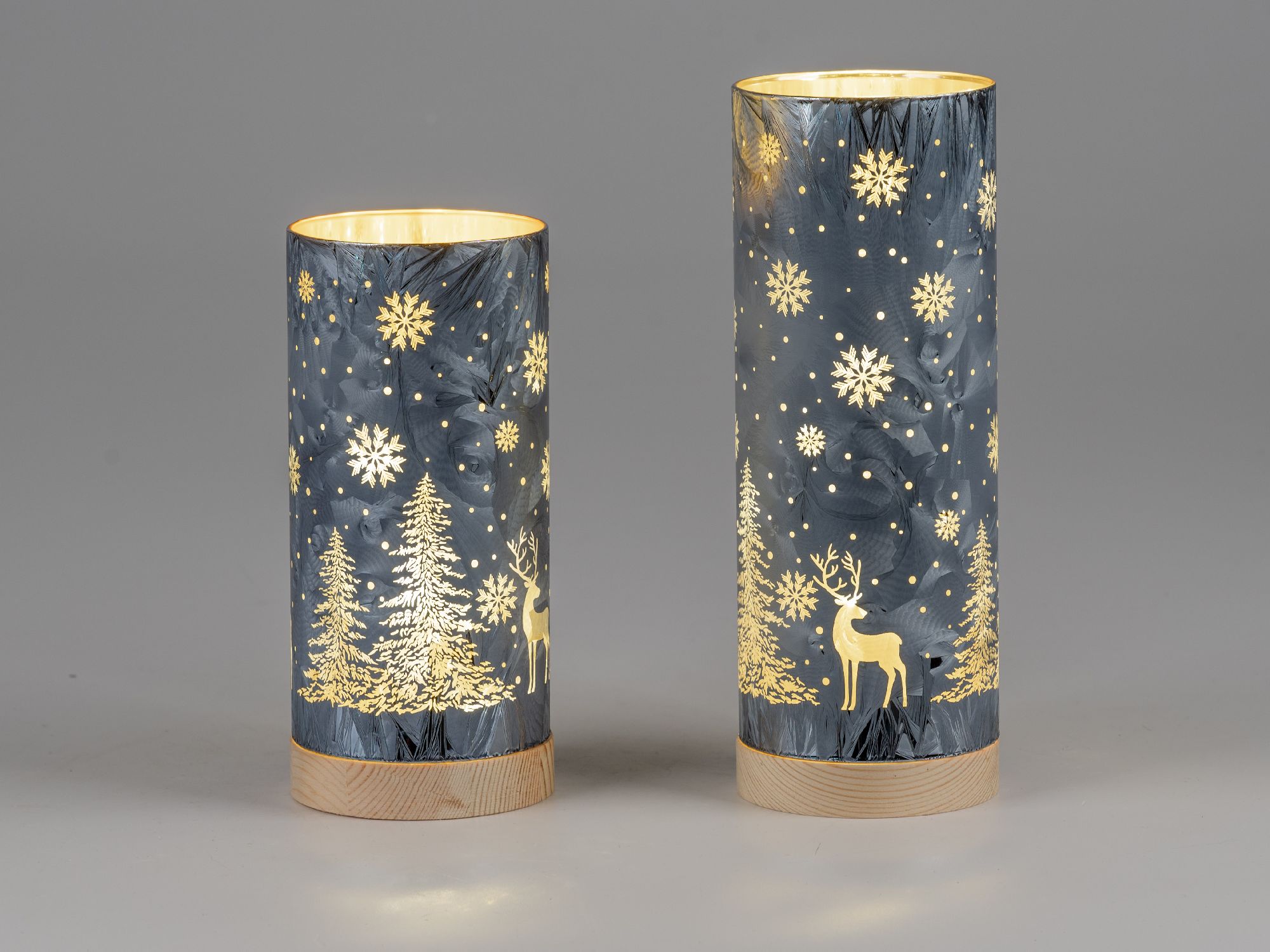 Zwei dekorative Laternen in zylindrischer Form mit winterlichen Motiven wie Bäumen, Schneeflocken un