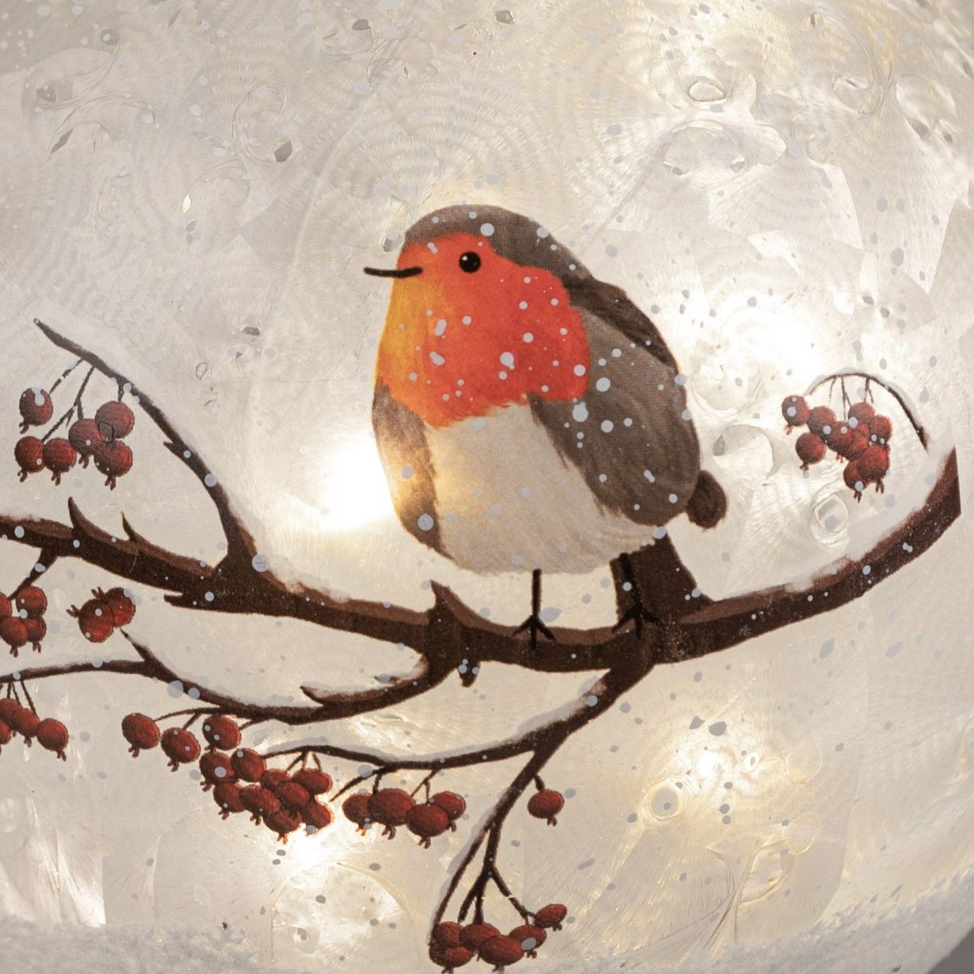 Ein Vogel mit roter Brust sitzt auf einem Ast, umgeben von Beeren und Schneeflocken. Der Hintergrund