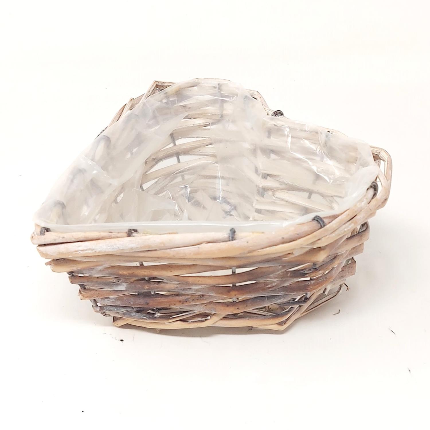 Ein herzförmiger Korb aus geflochtenem Material mit einer transparenten Innenauskleidung. Der Korb hat eine offene Form.