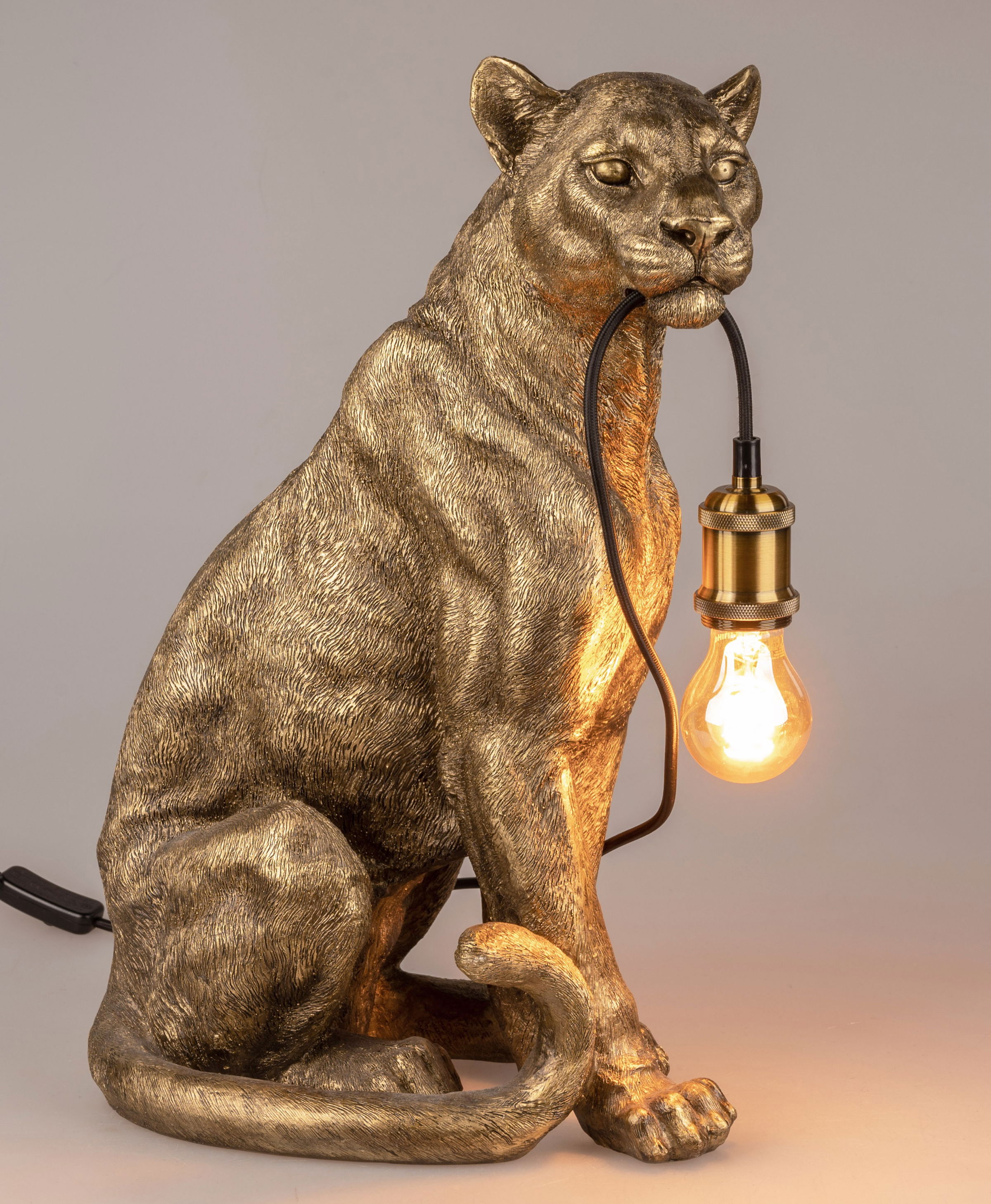 Eine goldene Lampe in Form eines sitzenden Panthers mit einer Glühbirne im Maul. Der Panther hat detaillierte Fellstrukturen.