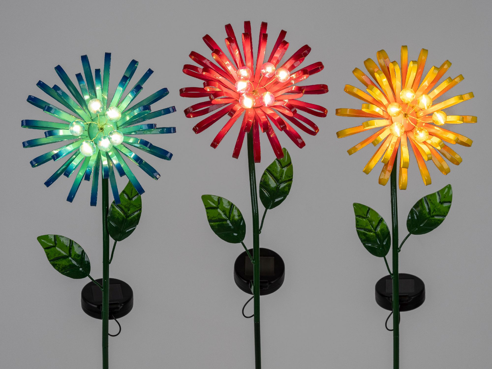 Drei bunte Blumen aus Kunststoff mit LED-Lichtern in Grün, Rot und Gelb, jeweils auf einem langen Stiel mit Blättern.