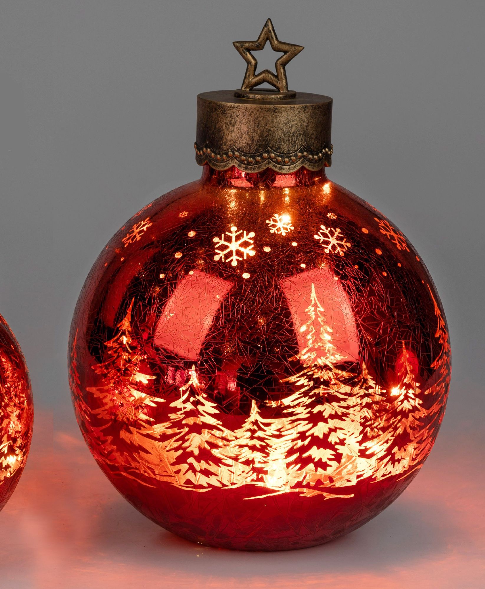 Rote Weihnachtskugel mit goldener Spitze, verziert mit Schneeflocken und Tannenbaum-Motiven, leuchte