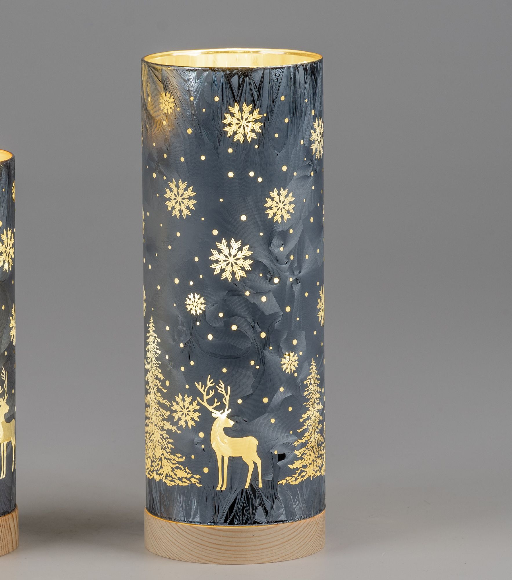 Zylindrische Lampe mit goldenen Schneeflocken, Tannenbäumen und einem Reh auf dunkelblauem Hintergru