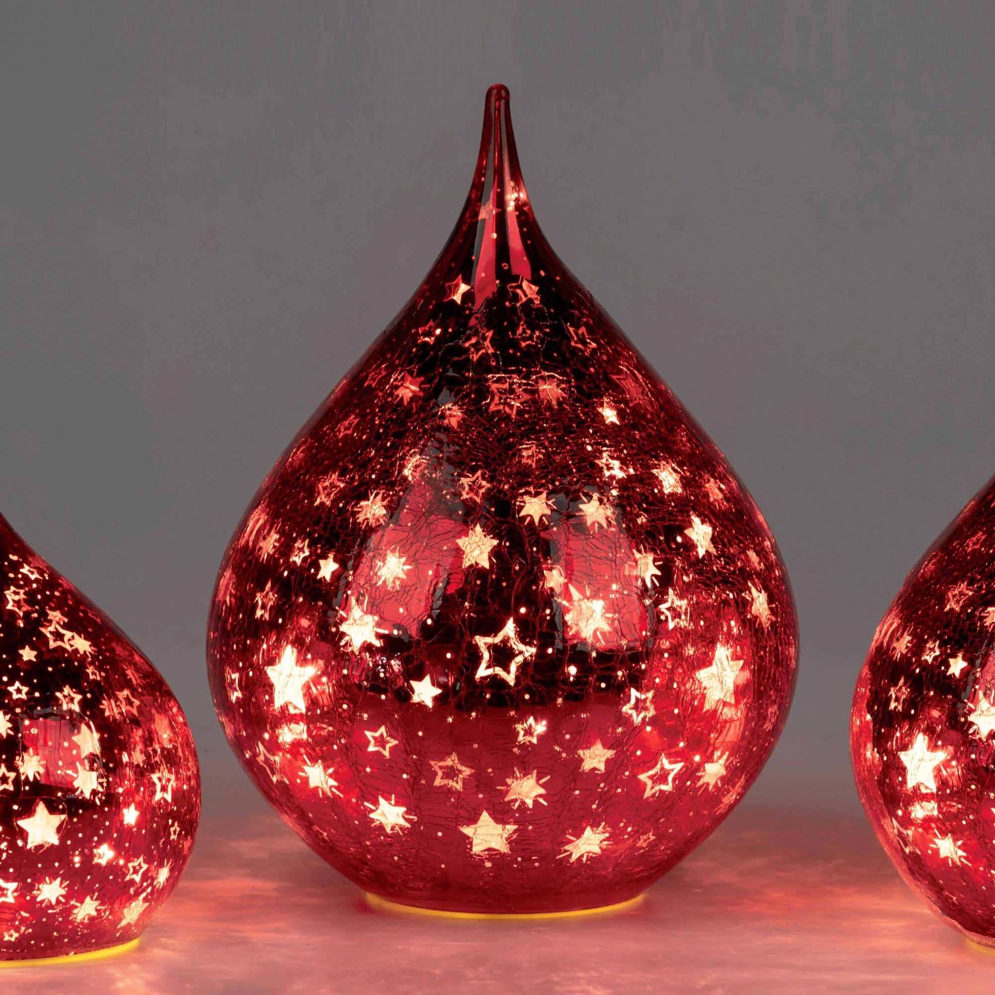 Drei rote, tropfenförmige Leuchten mit durchbrochenem Sternenmuster, die von innen beleuchtet sind.