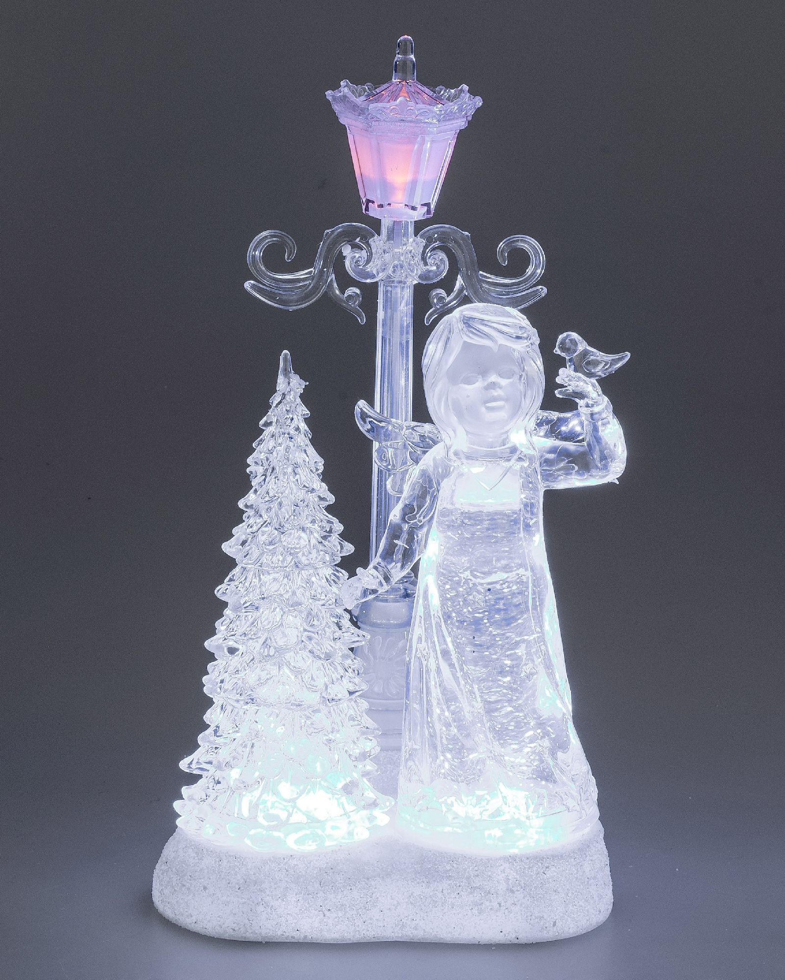 Dekorative Figur eines Engels mit einem Vogel, umgeben von einem Weihnachtsbaum und einer Laterne, a