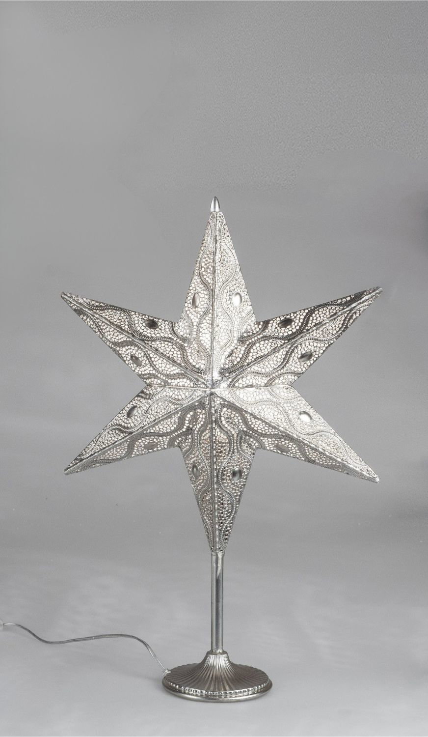 Eine silberne Sternlampe auf Ständer für Weihnachtsdeko mit grauem Fotostudio Hintergrund