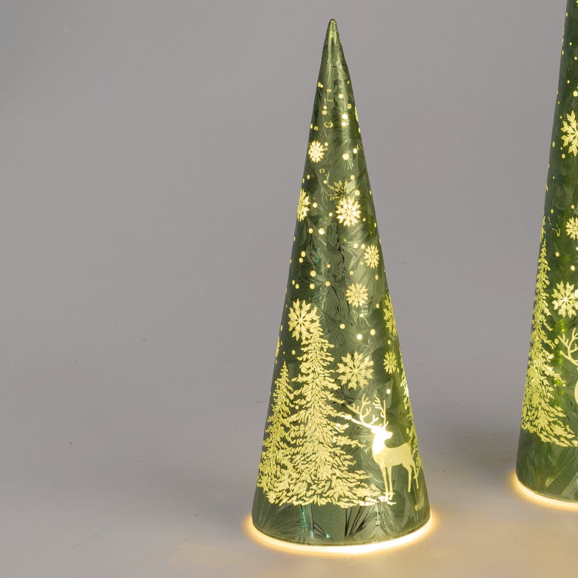 Zwei grüne, spitz zulaufende Weihnachtsdekorationen mit weißen Schneeflocken und einem Rentiermotiv,