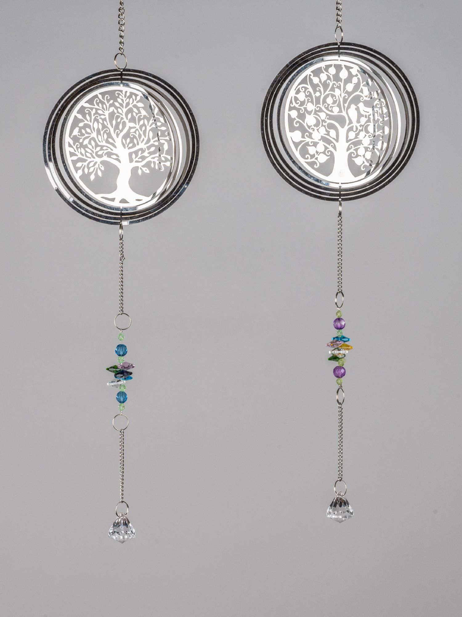 Zwei hängende Dekorationen mit Baum-Motiv aus Metall, verziert mit bunten Glasperlen und einem gläsernen Anhänger.