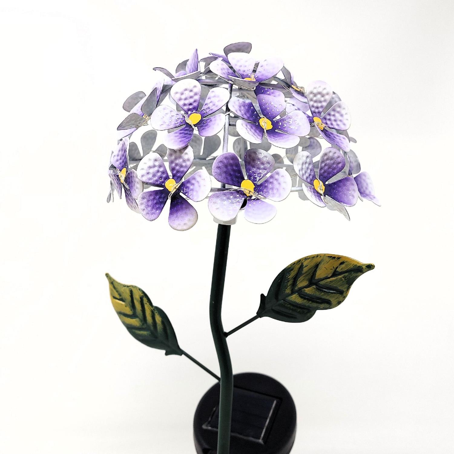 Eine dekorative Lampe in Form einer Blume mit lila Blüten und grünen Blättern auf einem schwarzen Sockel.