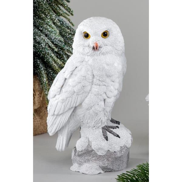 Weiße Eule auf einem grauen Sockel, mit großen gelben Augen und detaillierten Federn. Im Hintergrund