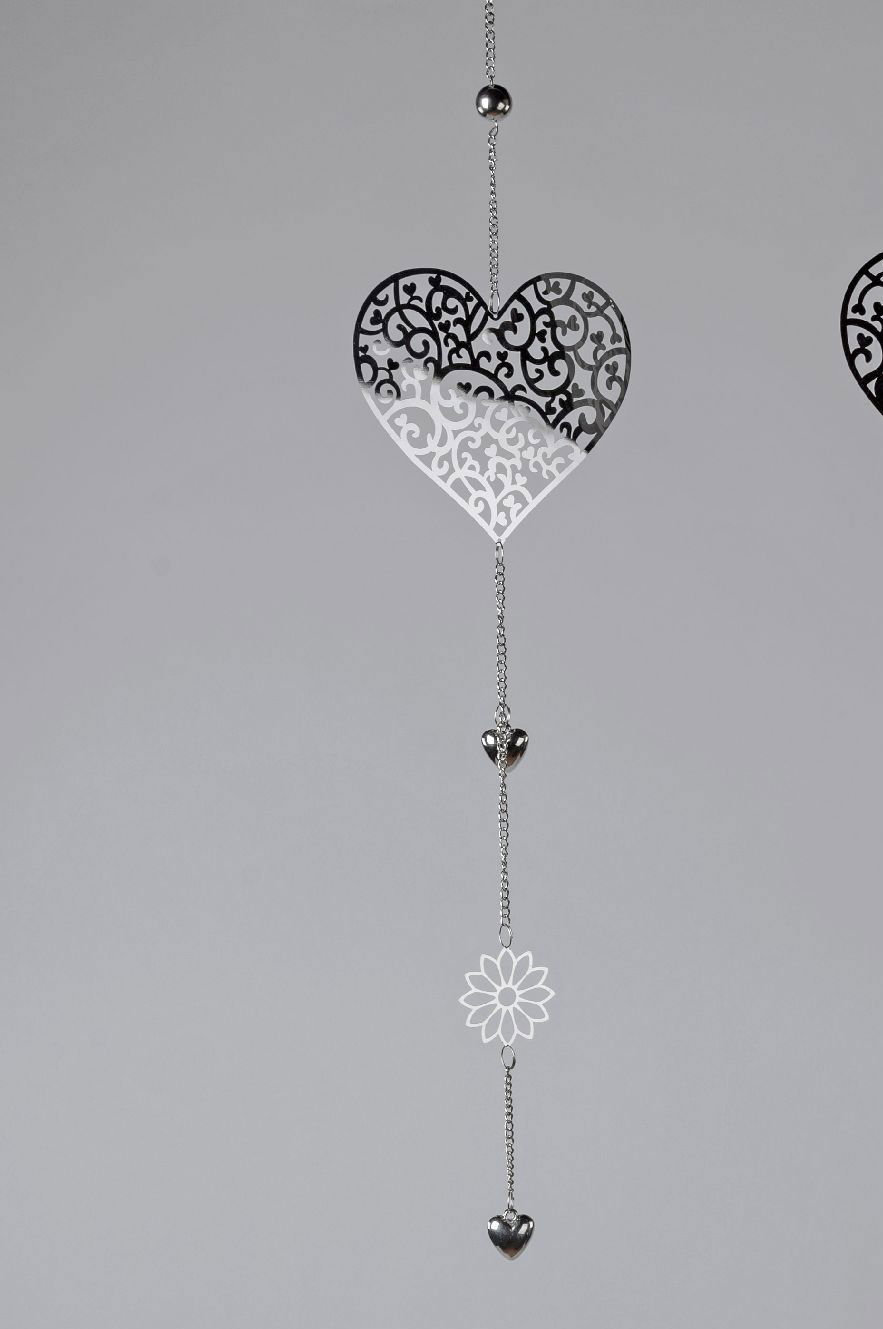 Hängende Dekoration mit zwei Herzen und einer Blume, aus transparentem und silberfarbenem Material, vor grauem Hintergrund.