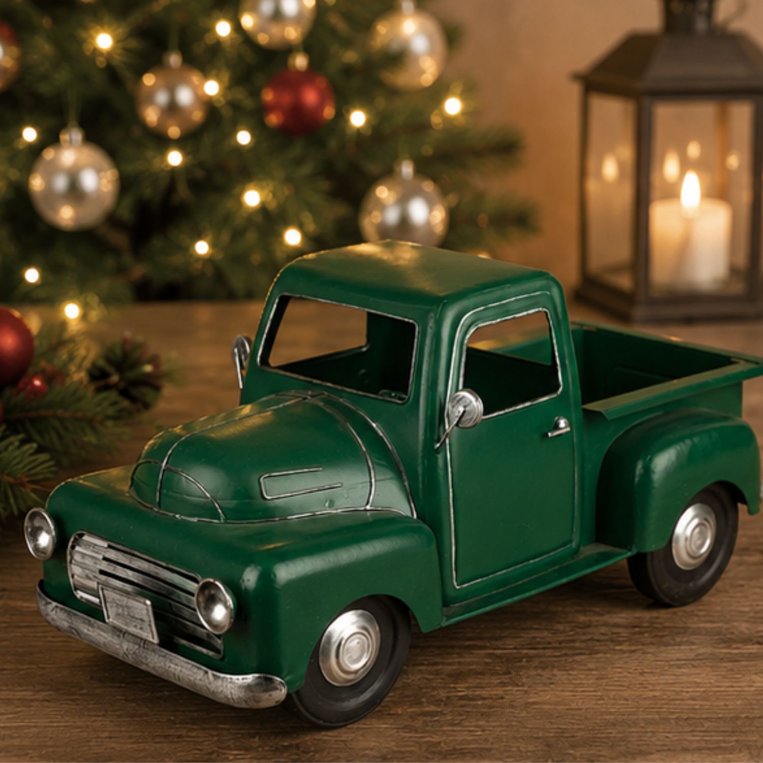 Grüner Spielzeug-Pick-up auf Holztisch, dahinter Weihnachtsbaum und Laterne mit Kerze