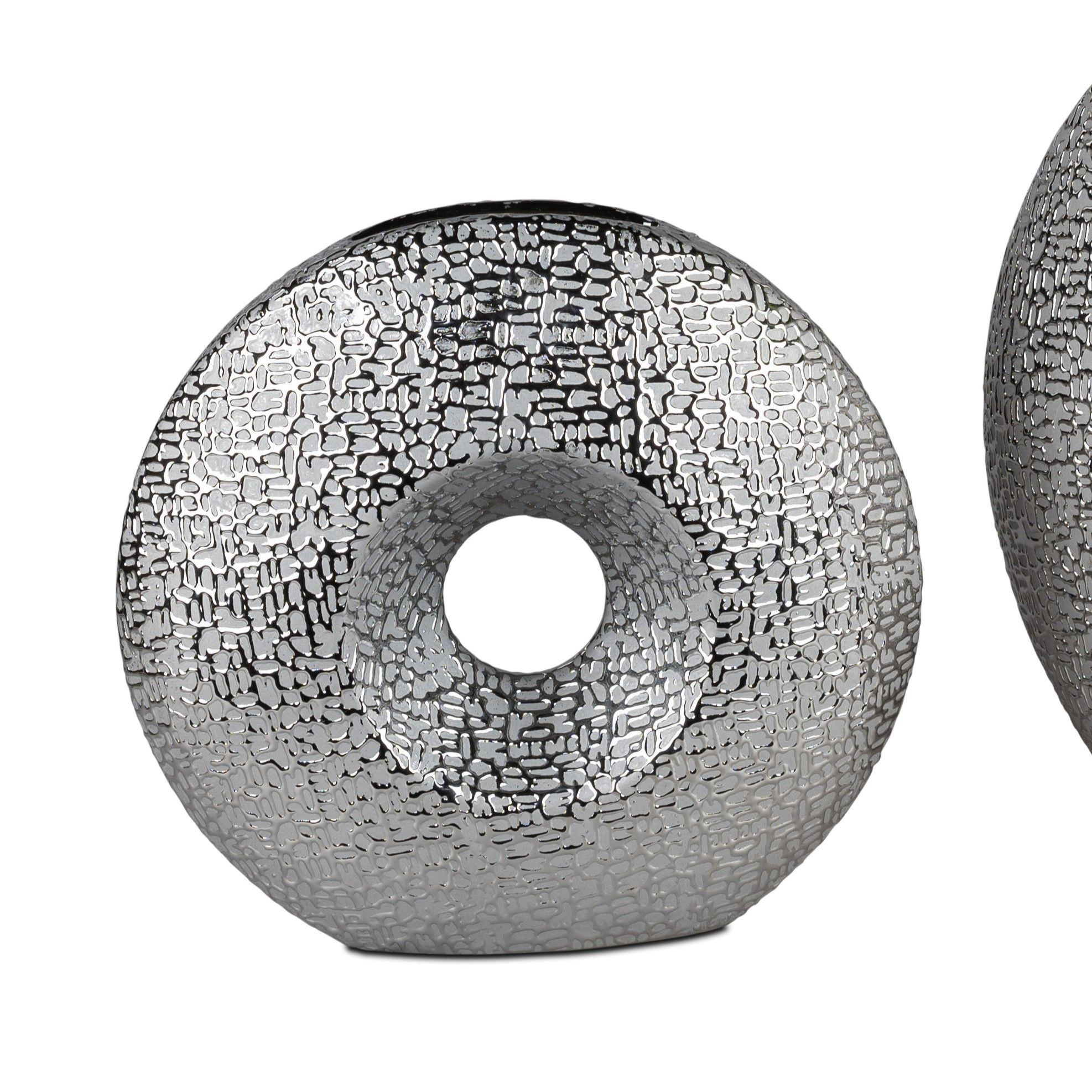 Zwei dekorative Objekte in Form von Donuts, aus silbernem Material mit strukturierten Oberflächen und einem zentralen Loch.