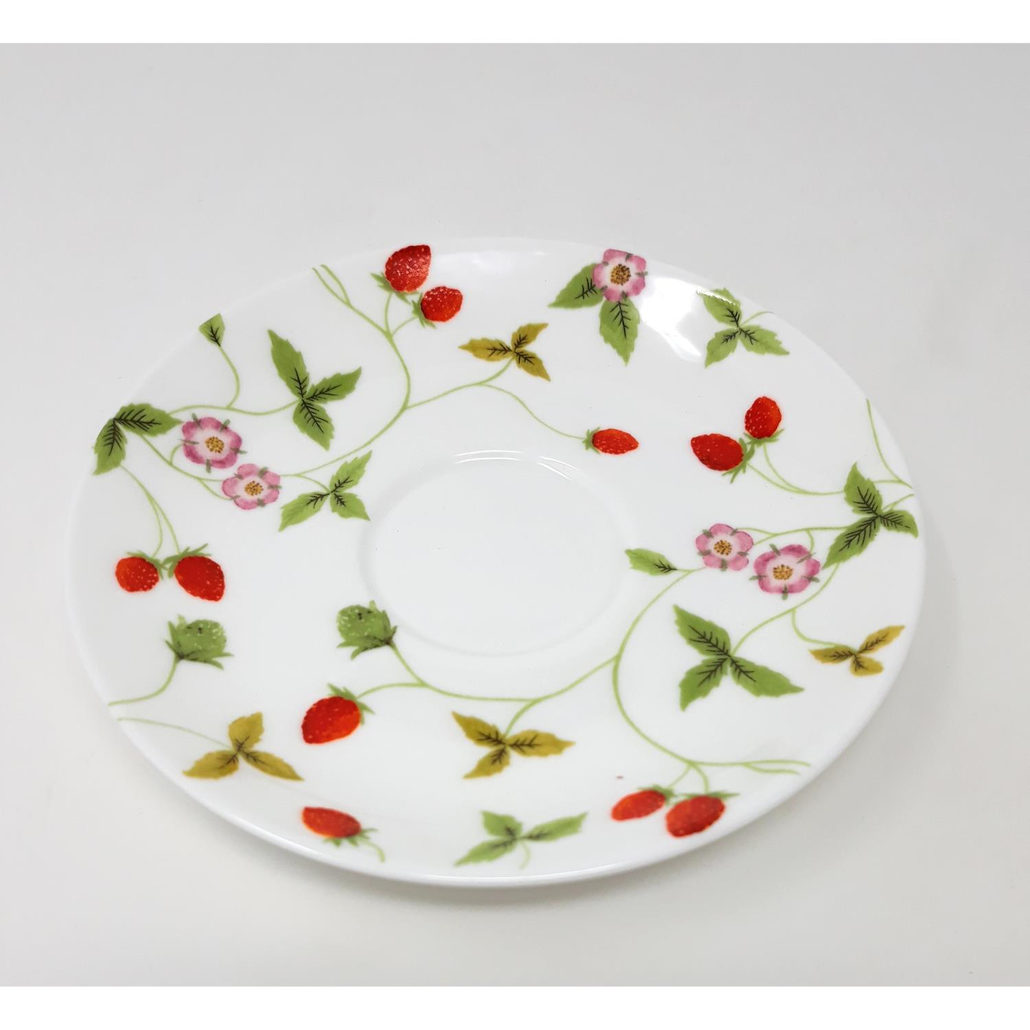 Ein flacher Teller mit einem weißen Grund und bunten Motiven von Erdbeeren und Blumen in Rosa und Grün.