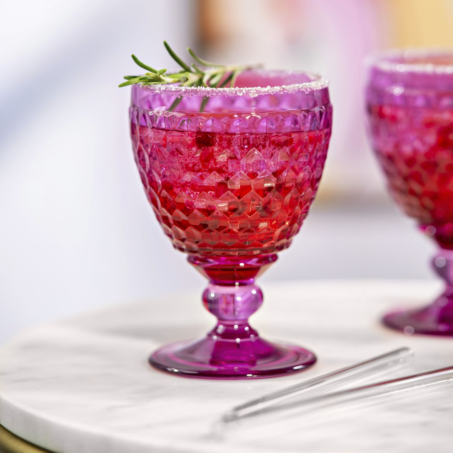 Rosa Getränk in einem dekorativen Glas mit Rosmarin und Zuckerrand