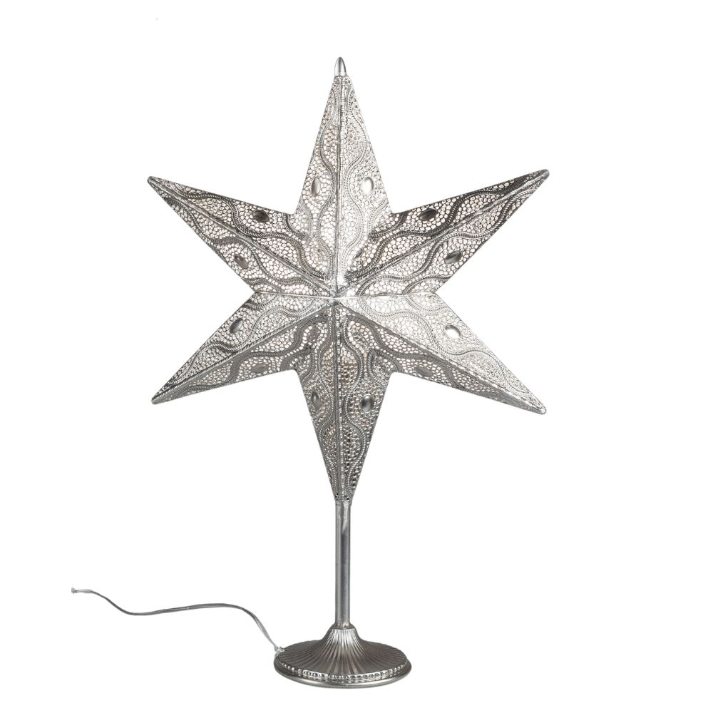 Ein silberner, filigraner Stern mit spitzen Zacken steht auf einem runden Sockel. Er hat ein Kabel u