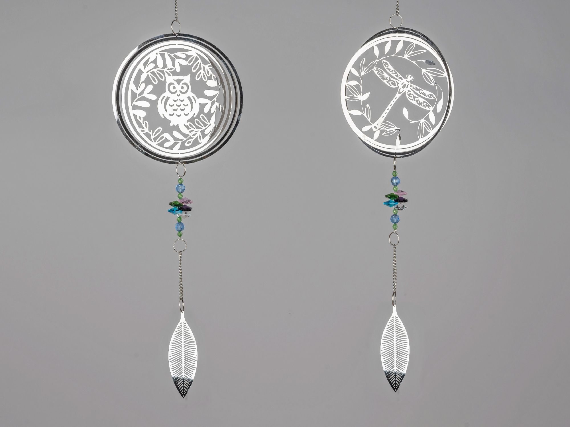 Zwei hängende Dekorationen aus Metall mit durchbrochenen Mustern von einer Eule und einer Libelle, verziert mit bunten Perlen.