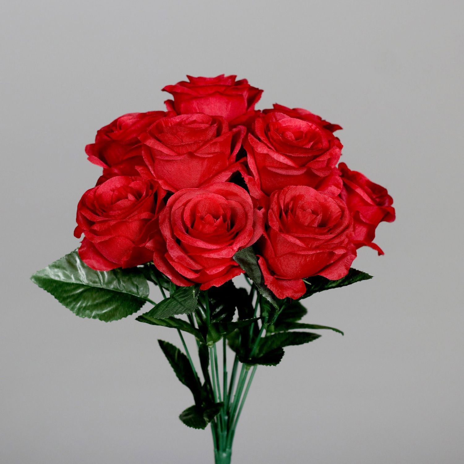 Bouquet aus roten Rosen mit grünen Blättern vor grauem Hintergrund