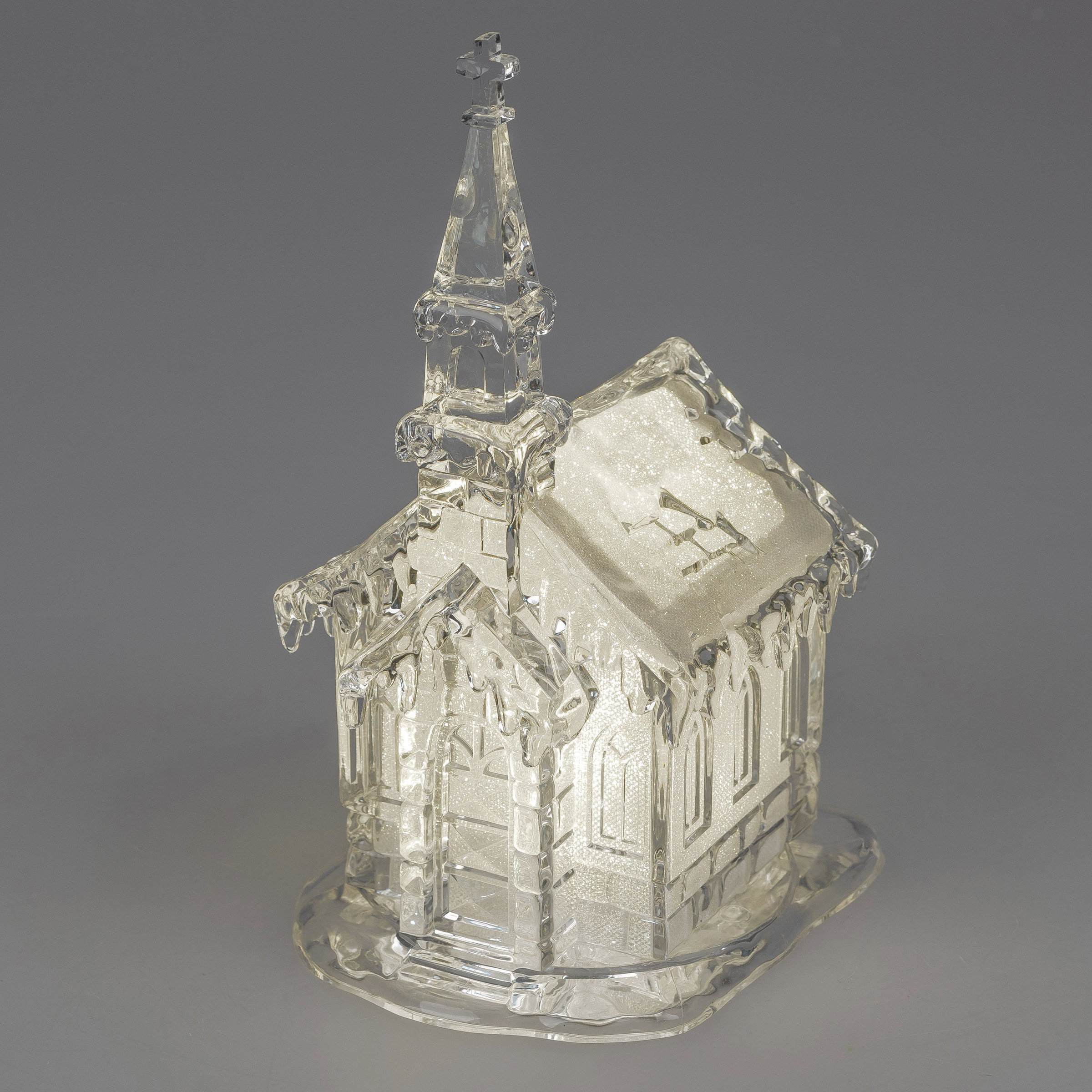 Eine gläserne Kirche mit einem spitzen Turm und einem Kreuz, verziert mit frostigen Details und eine