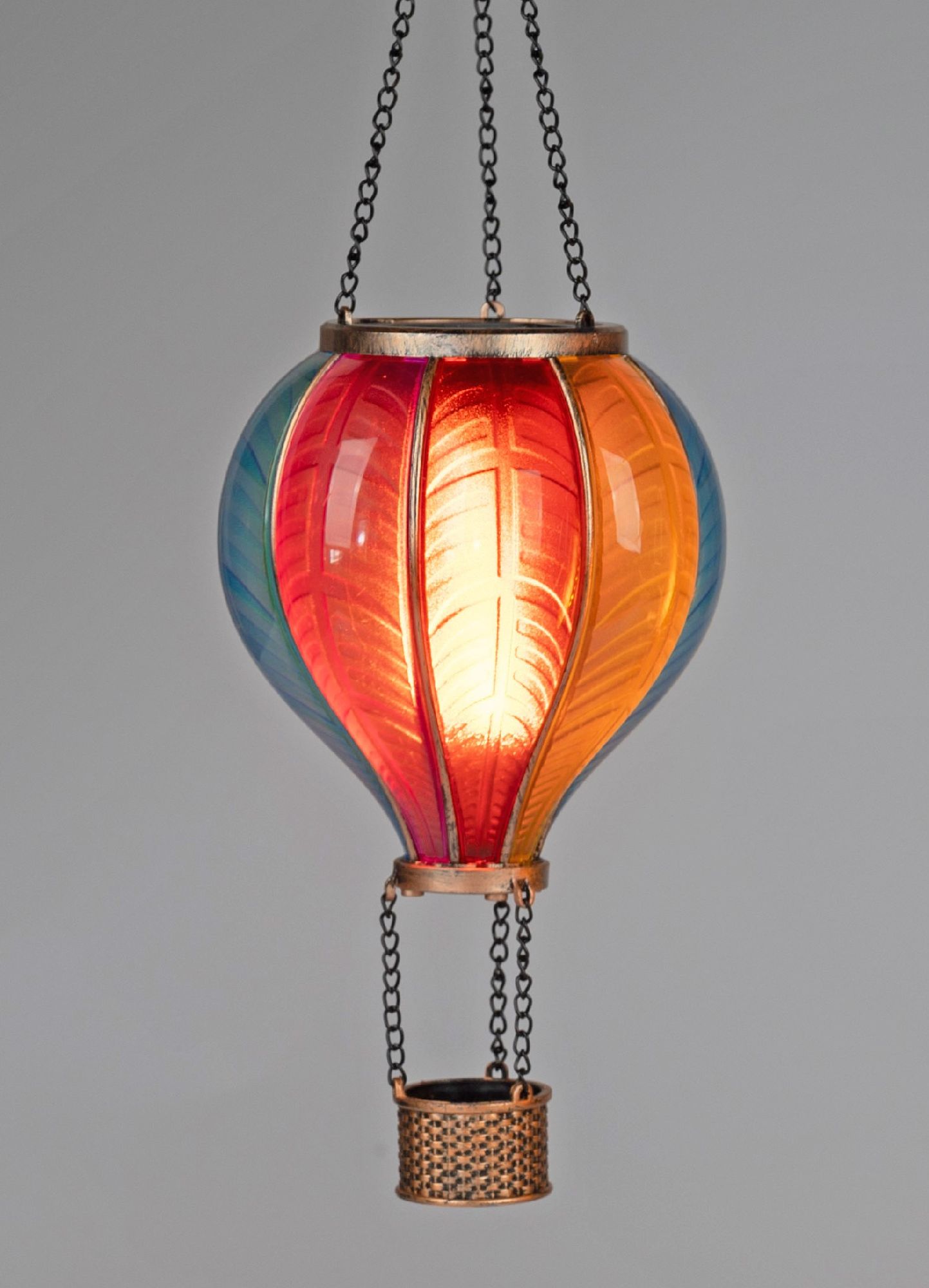 Hängende Lampe in Form eines Heißluftballons, bunt gestaltet mit rot, orange und blau, leuchtet von innen.