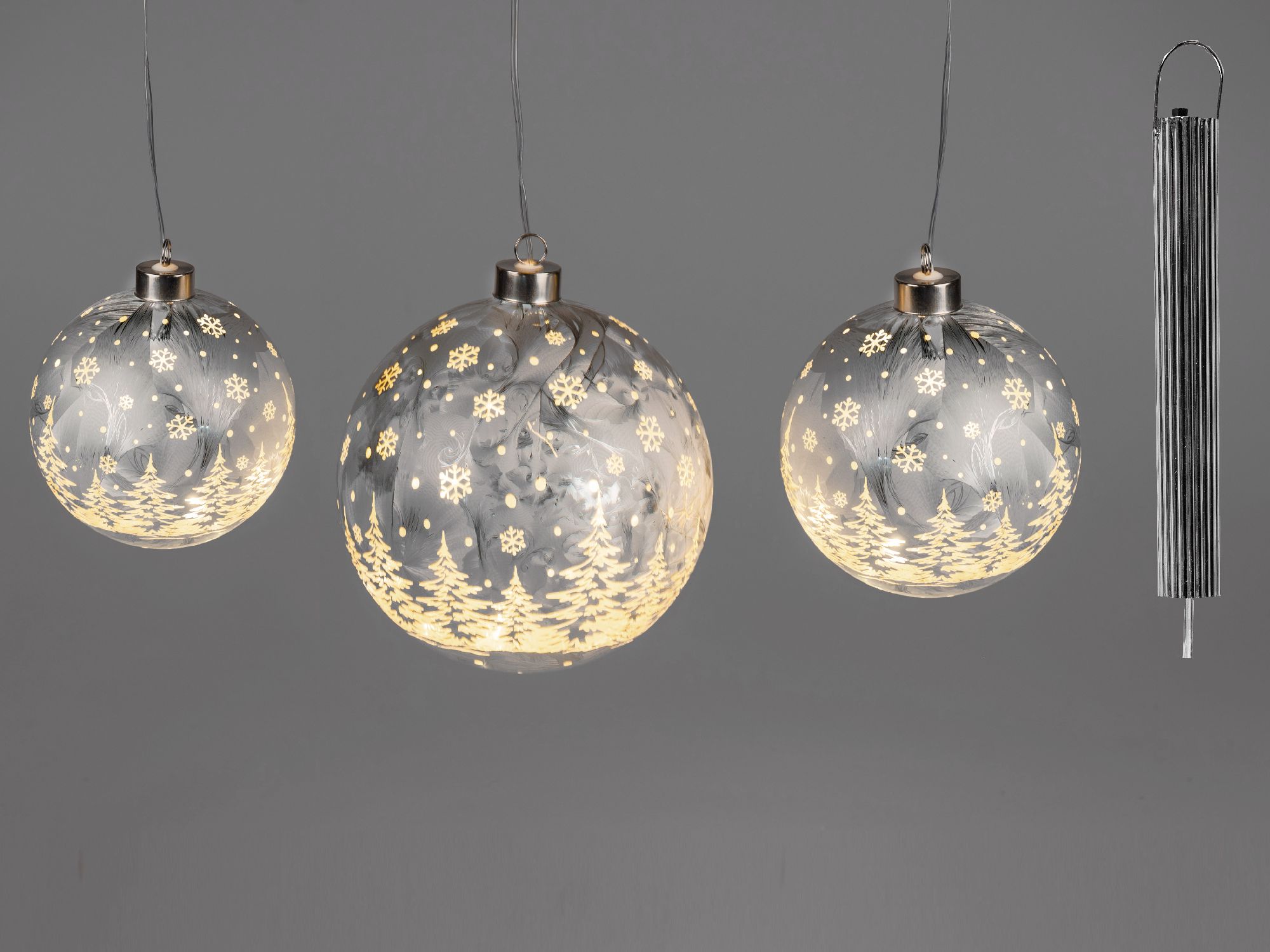 Drei silbergraue LED Kugeln zum aufhängen mit Schneeflocken- und Tannenbaum-Motiven