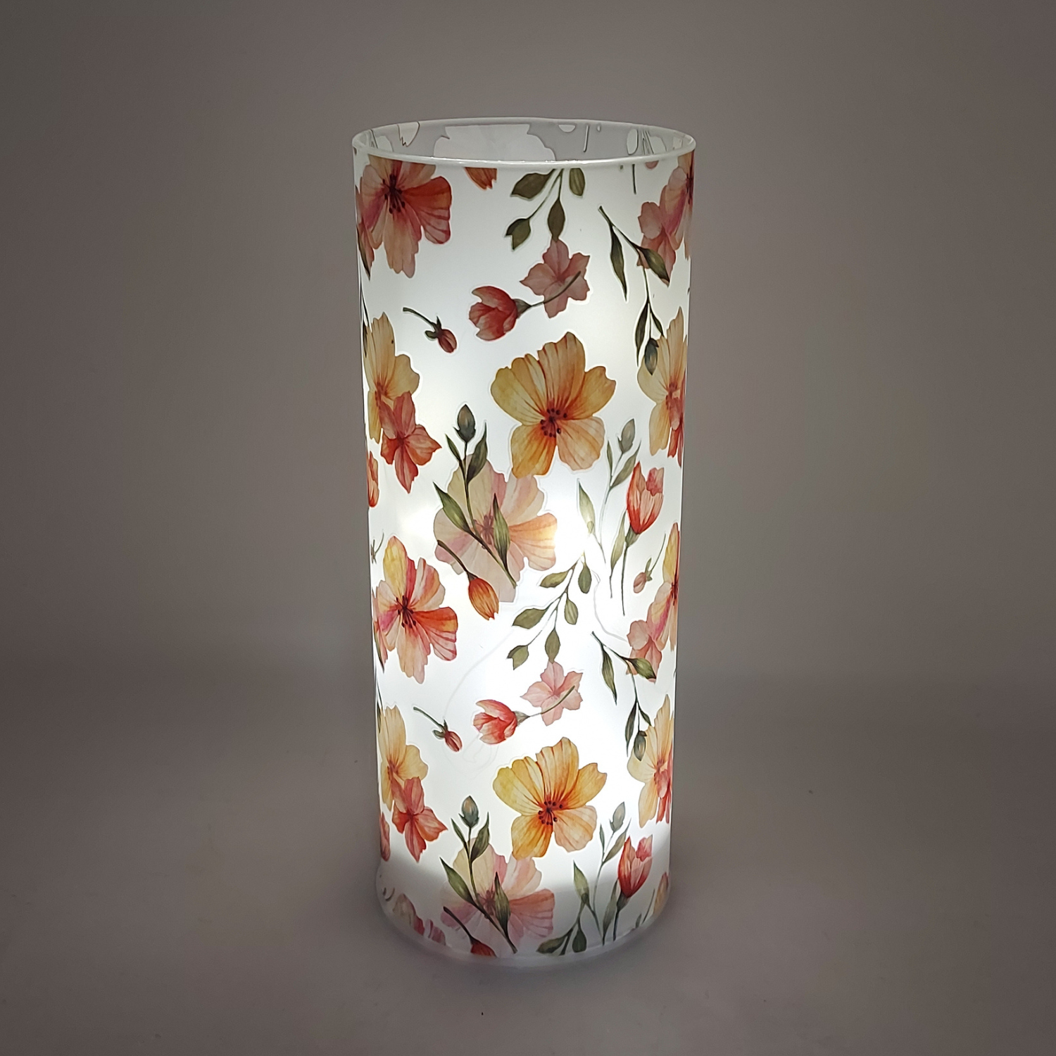 weiß transparenter Glaszylinder mit Blumenmotiven beleuchtet auf schwarzem Hintergrund