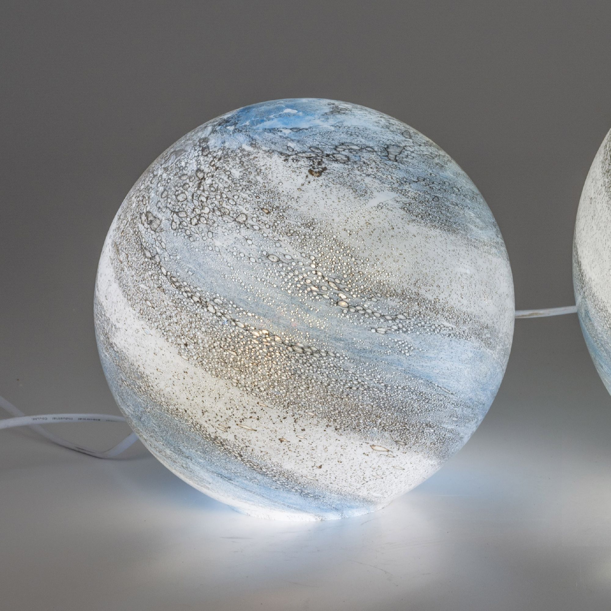 Runde Lampe mit blauen und weißen Farbverläufen sowie einer strukturierten Oberfläche, die Licht abstrahlt.