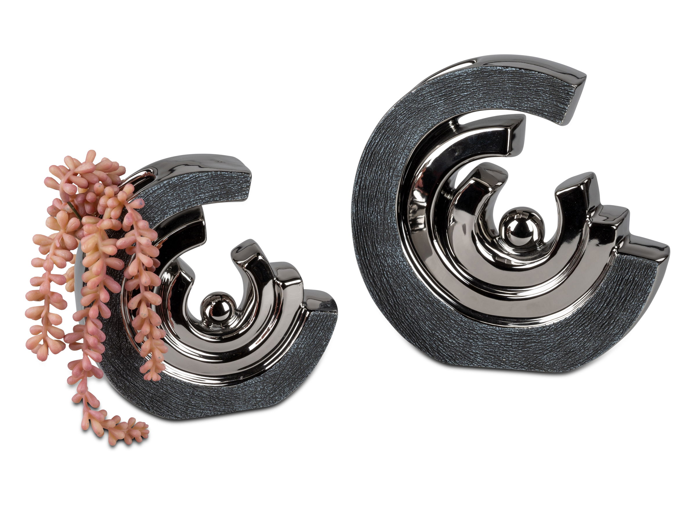 Zwei dekorative Objekte in spiralförmiger Form, eines mit glänzender Oberfläche und das andere mit einer Pflanze in sanften Farben.