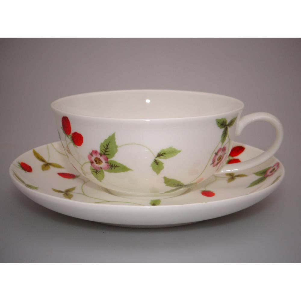 Eine weiße Tasse mit einem Unterteller, verziert mit roten Beeren und grünen Blättern sowie rosa Blüten.