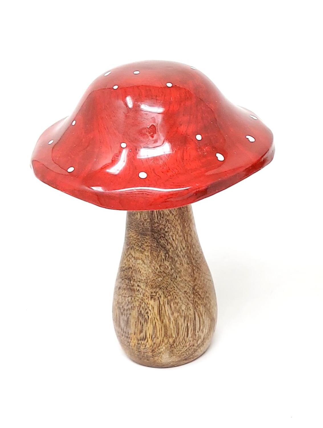 Ein rot lackierter Holzpilz mit weißen Punkten auf dem Hut und einem braunen, glatten Stiel.