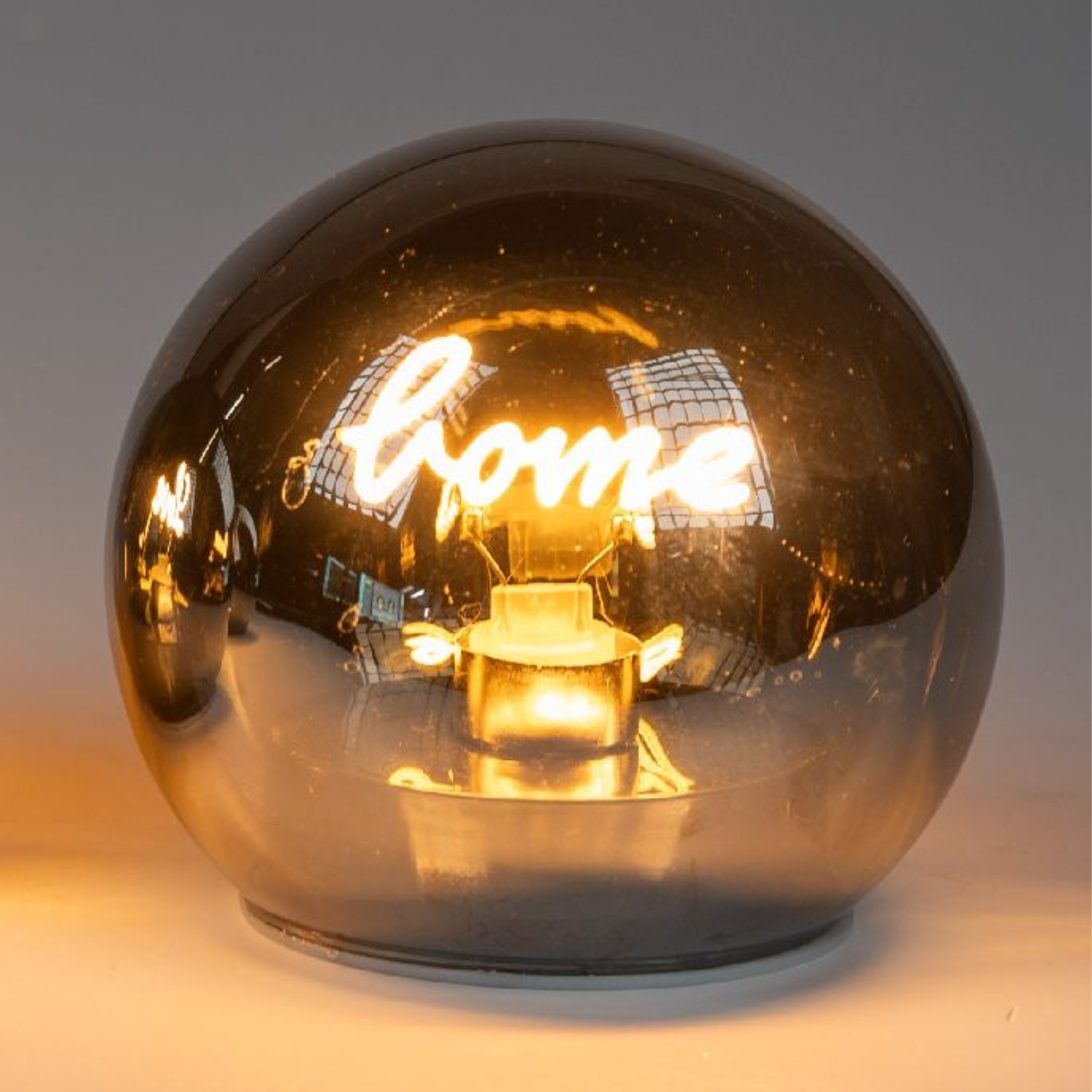 Zwei runde, glänzende Lampen mit goldfarbener Oberfläche, die eine warme Lichtquelle im Inneren haben.