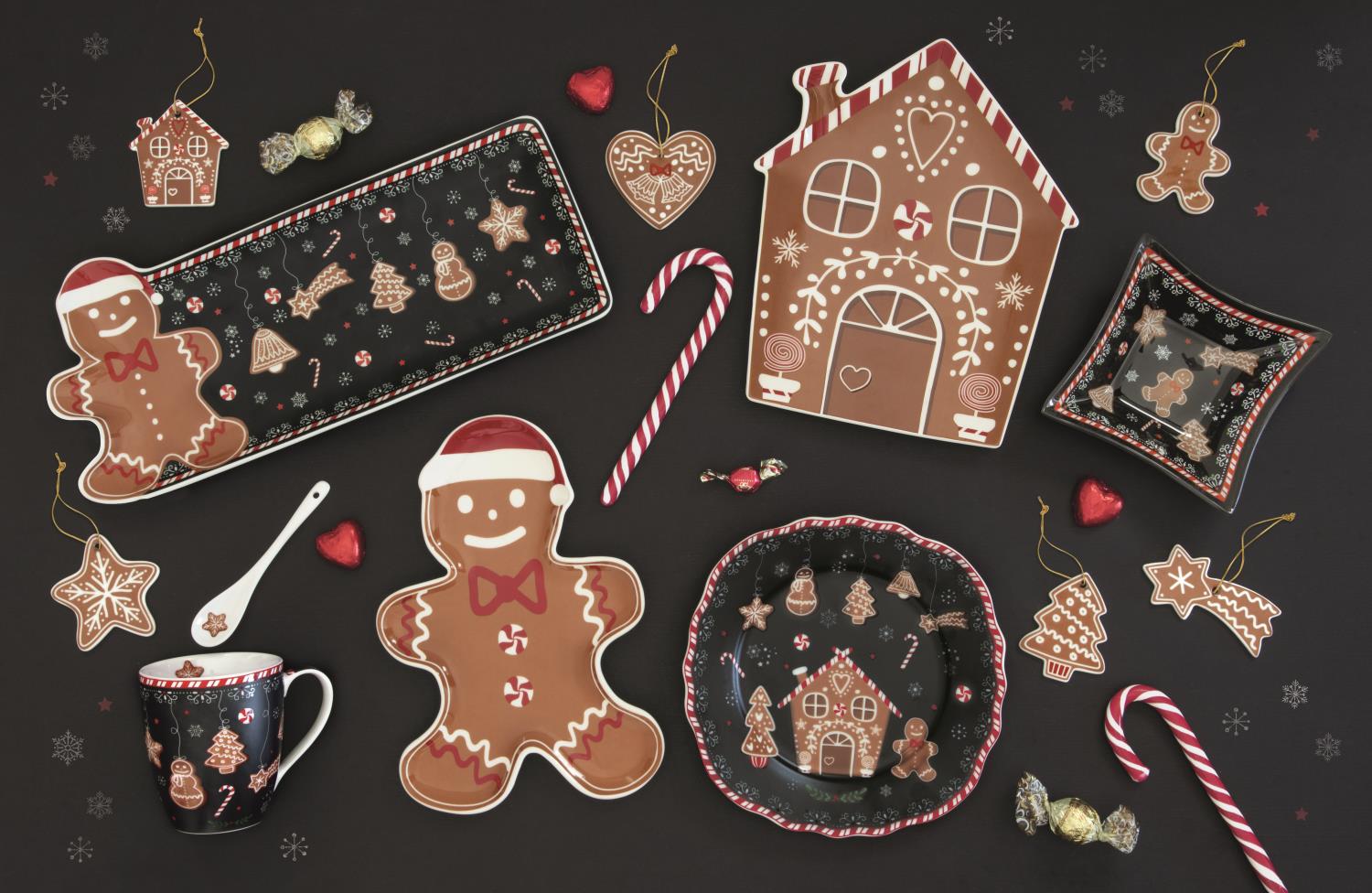 Dekorative Weihnachtsplätzchen, Geschirr und Süßigkeiten auf schwarzem Hintergrund, darunter ein Lebkuchenhaus und Figuren.