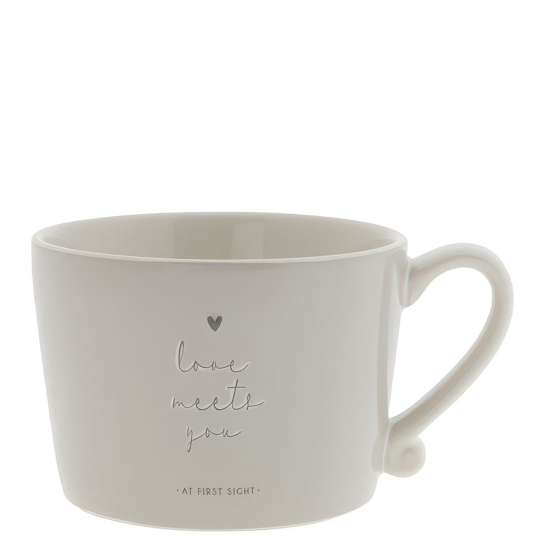 Beige Tasse mit einem Henkel, bedruckt mit dem Text „love meets you“ und einem kleinen Herz.