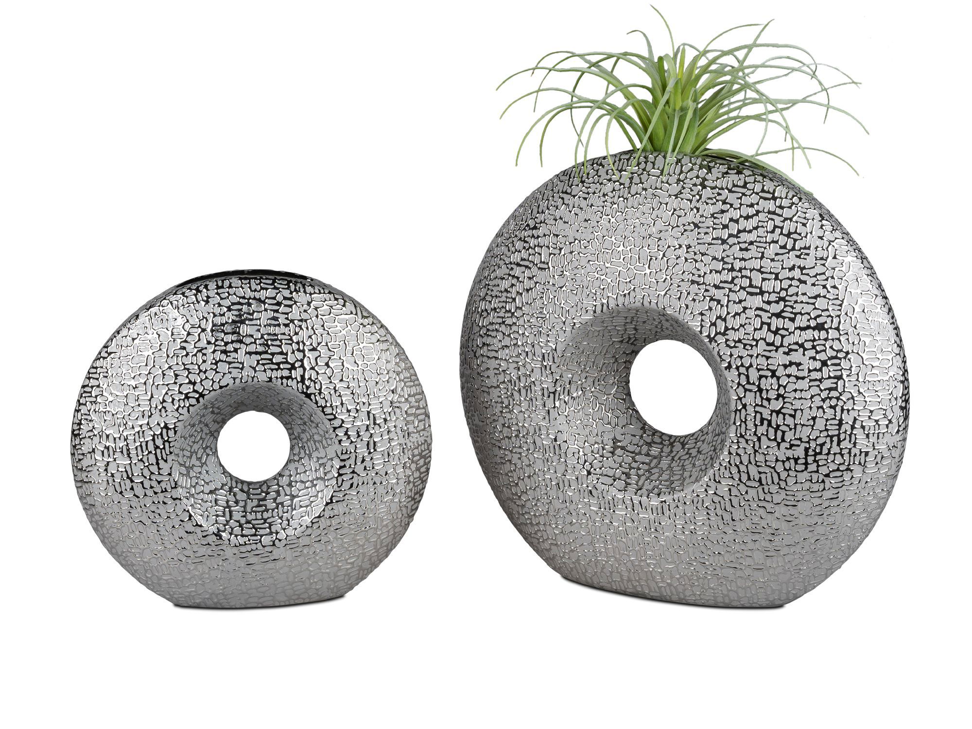 Zwei dekorative Objekte in Form von Donuts, eines klein und rund, das andere größer und oval, beide mit einer strukturierten Oberfläche.