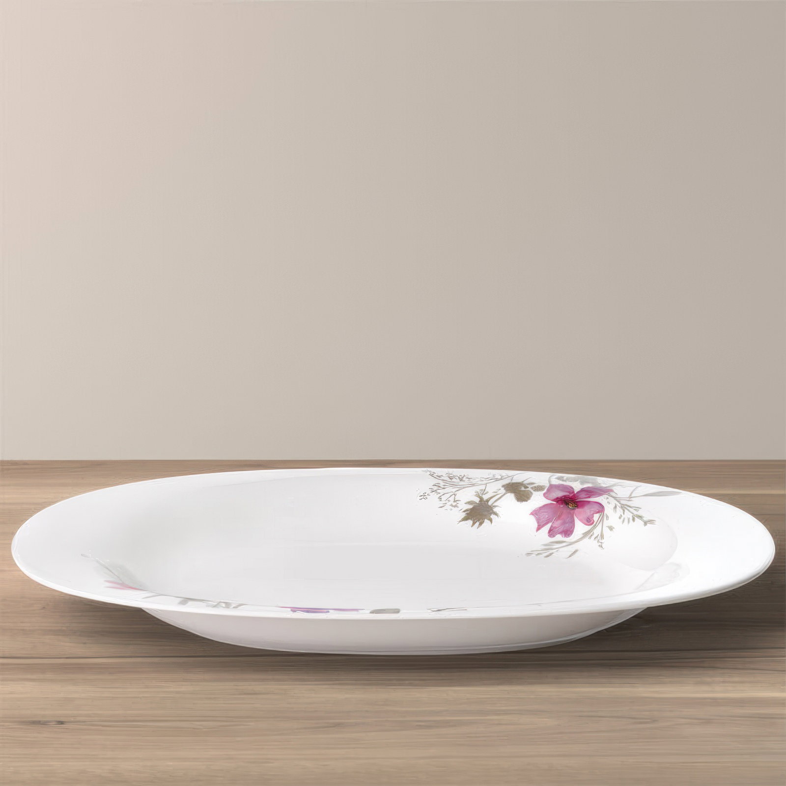 Flaches, ovales Geschirr aus weißem Porzellan mit floralem Muster in Rosa und Grau, auf einem Holzun