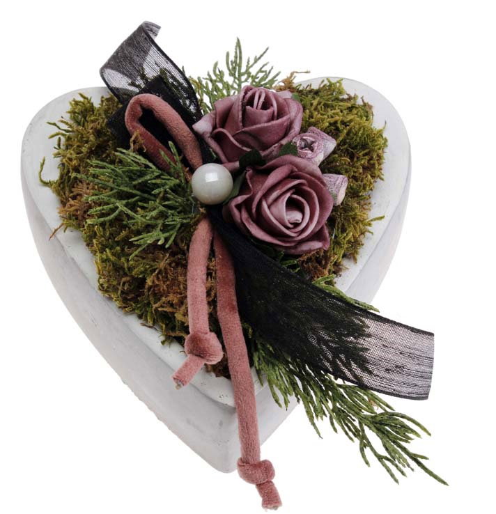 Herzförmige Dekoration aus Moos, mit rosa Rosen, einer Perle und einem schwarzen Band verziert.