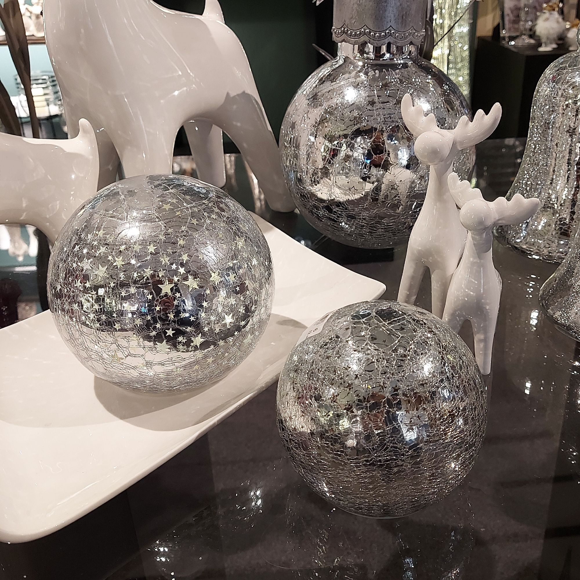 Dekorative Objekte: zwei glitzernde Kugeln, ein weißes Rentier und weitere glänzende Figuren auf ein