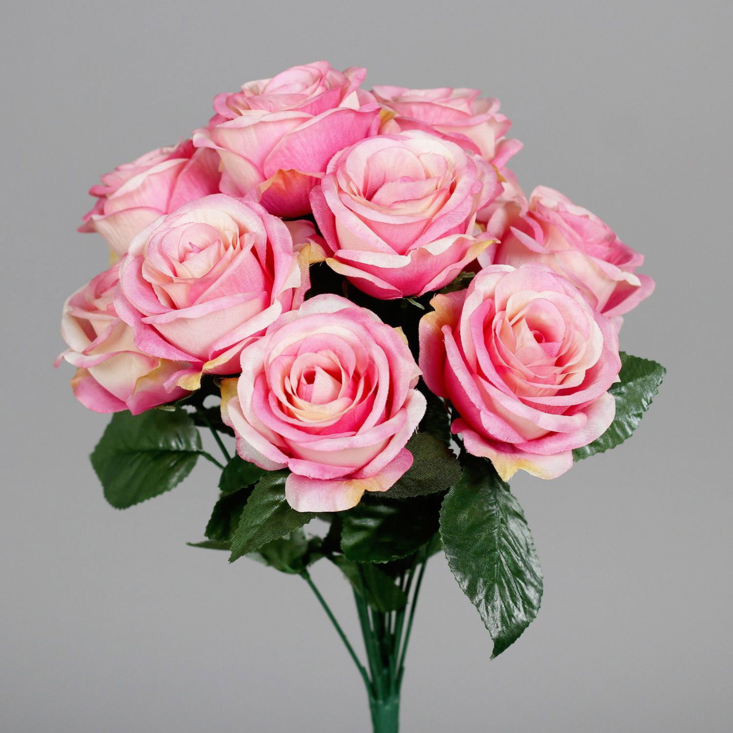 Strauß rosafarbener Rosen mit grünen Blättern vor grauem Hintergrund