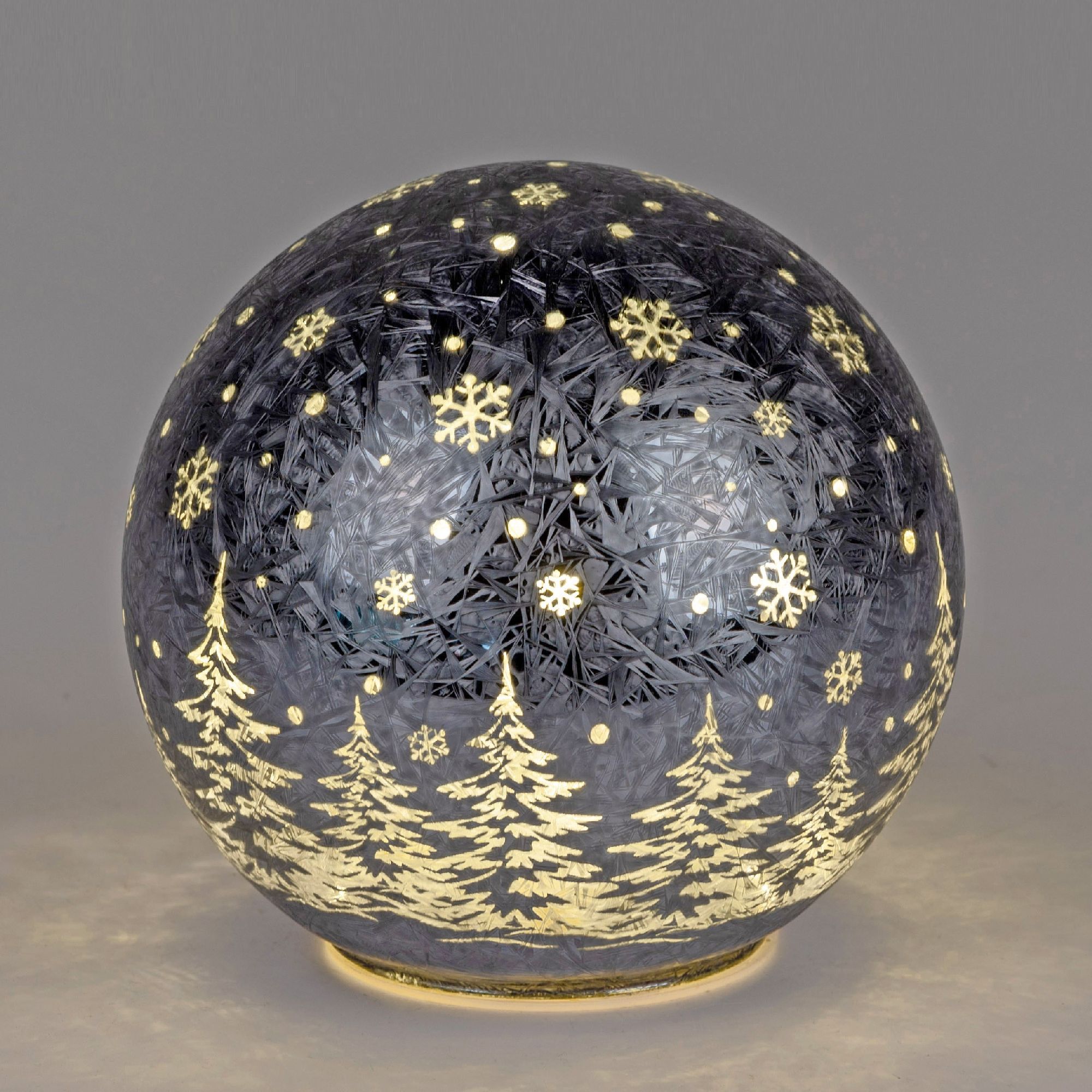 Glaskugel mit winterlichem Motiv: Schneeflocken und Tannenbäume in Gold auf dunklem Hintergrund.