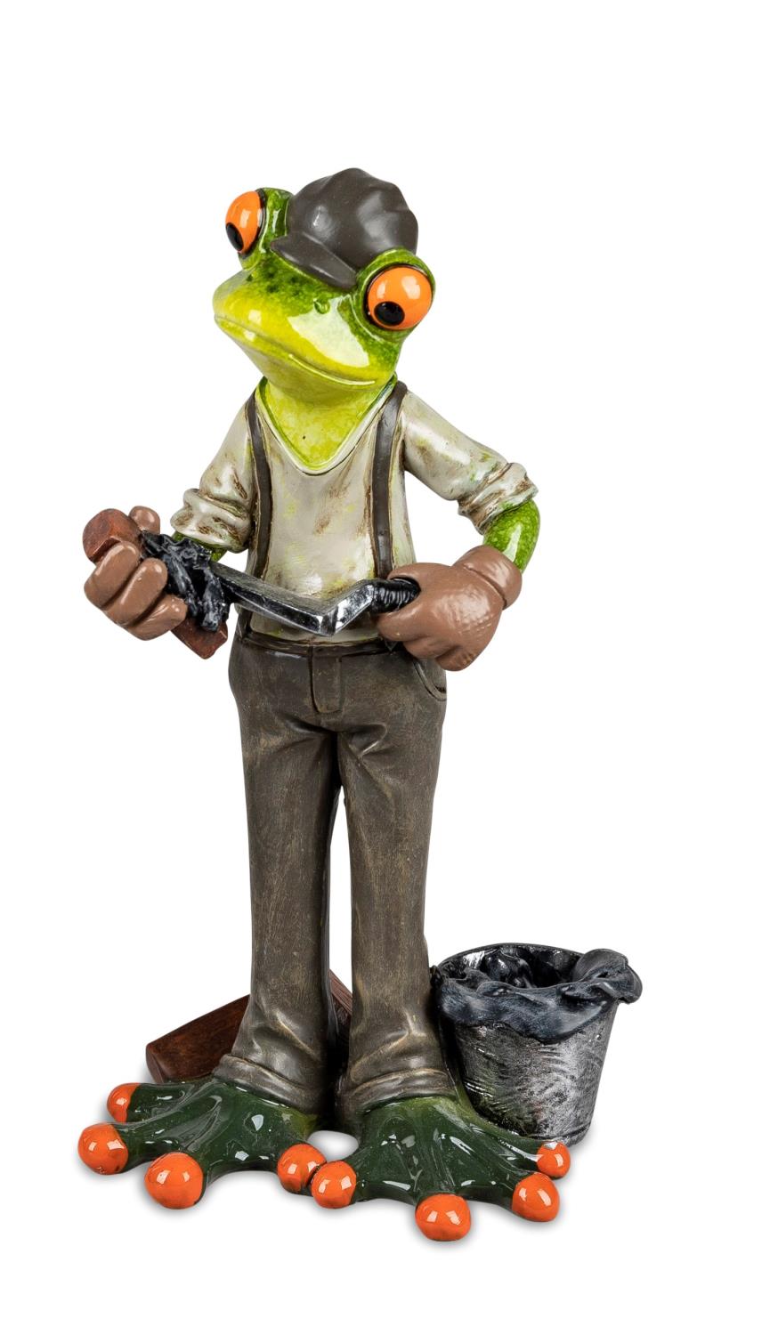 Eine Figur eines Frosches in Arbeitskleidung, der ein Werkzeug hält. Er steht neben einem Mülleimer und hat orangefarbene Füße.