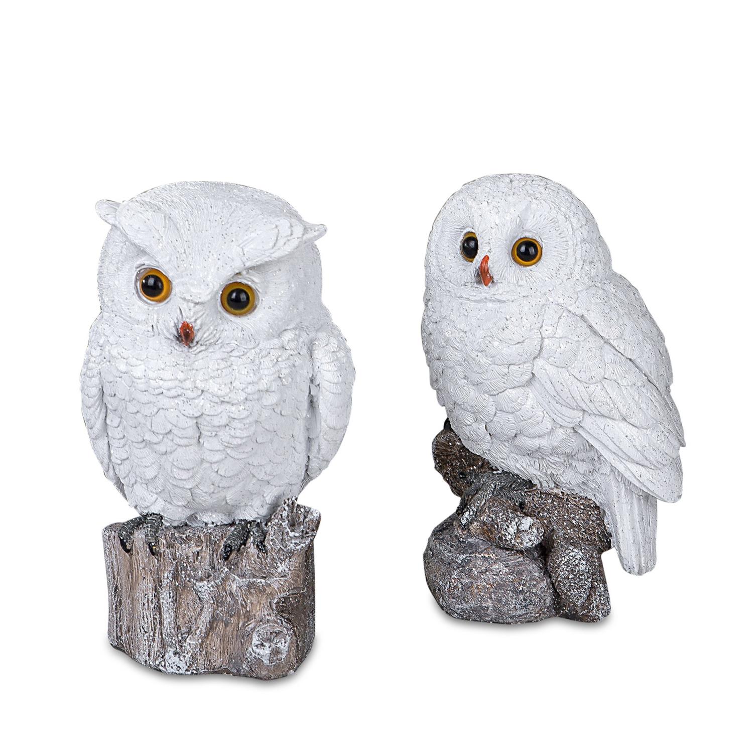 Zwei weiße Eulenfiguren aus Kunststein, eine sitzt auf einem Baumstumpf, die andere steht daneben. B