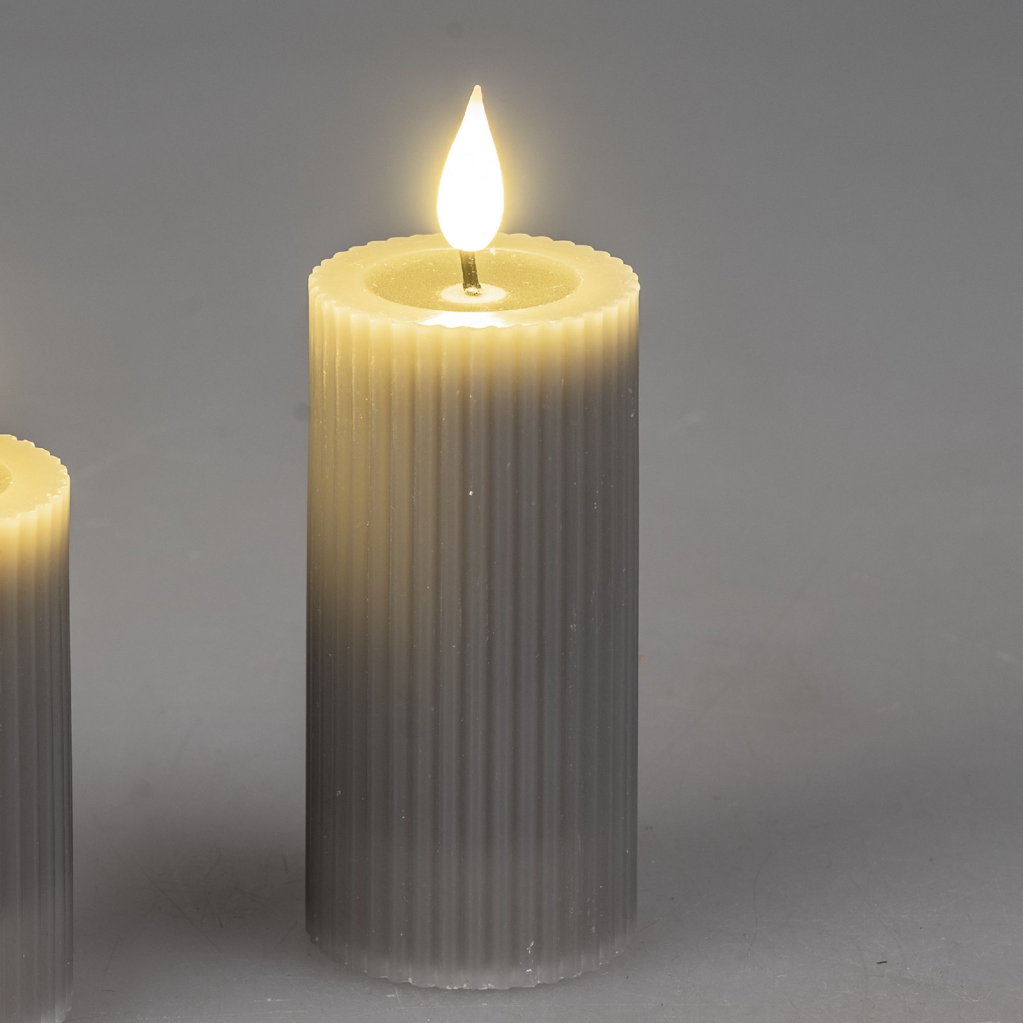 Zwei dekorative, flammenlose Kerzen in zylindrischer Form, eine größer und eine kleiner, mit sanftem Licht.