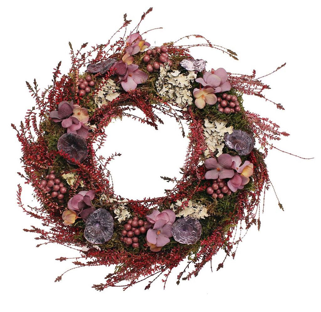 Ein runder Kranz aus roten und lila Blumen, Beeren und Moos, dekoriert mit verschiedenen Pflanzenmaterialien.